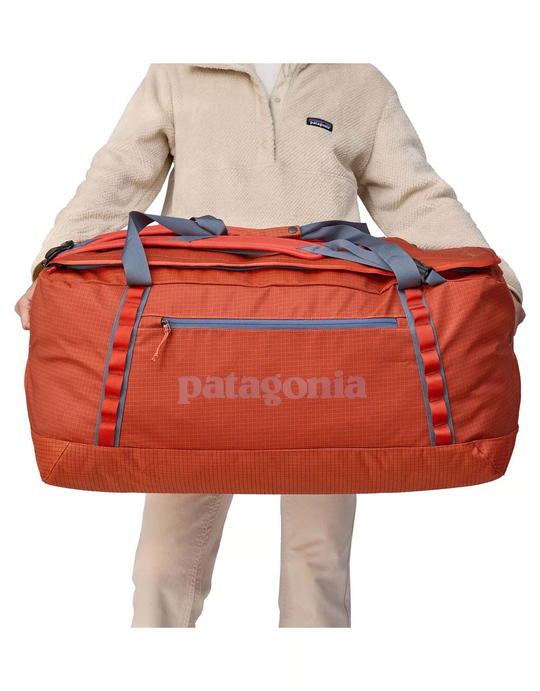 Black Hole Duffel 100L in recycled water-repellent fabric being held.