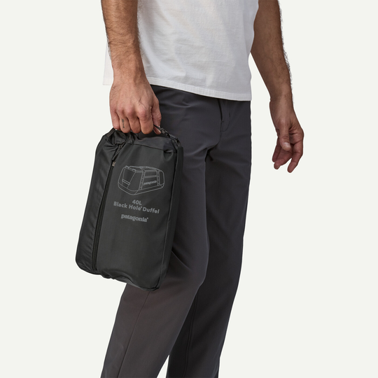 Compact Black Hole Duffel 40L held by a person, showcasing portability and convenient size for travel.