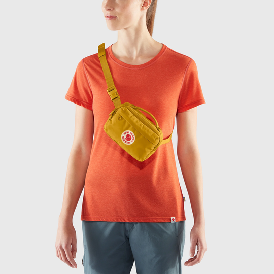 Kånken Hip Pack in yellow worn across the chest with adjustable strap, features durable Vinylon F fabric.