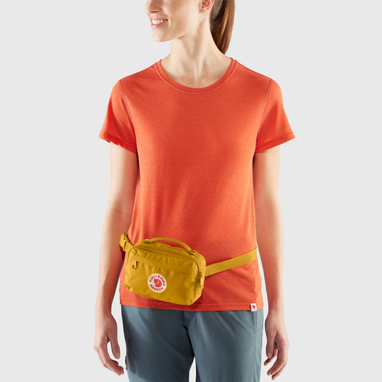 Kånken Hip Pack in yellow worn by person in orange shirt.