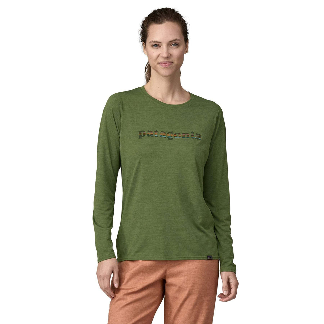 Woman wearing the green "W's L/S Cap Cool Daily Graphic Shirt" with moisture-wicking and odor control technology, made from recycled polyester.