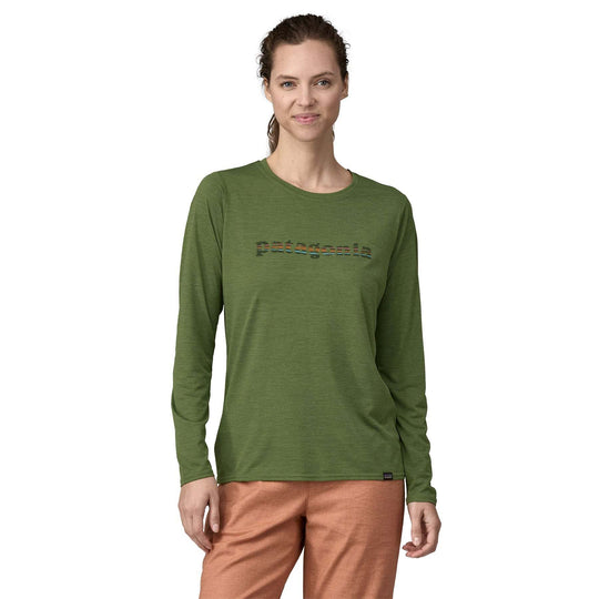 Woman wearing the green "W's L/S Cap Cool Daily Graphic Shirt" with moisture-wicking and odor control technology, made from recycled polyester.