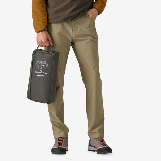Black Hole Duffel 70L held by person, compact design, fair trade, eco-friendly materials.