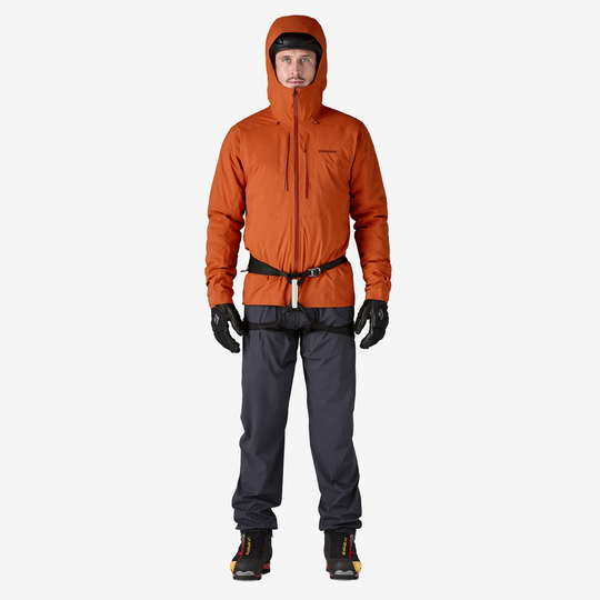 M's M10 Storm Jkt alpinismo arancione, cappuccio regolabile, zip impermeabile, uomo con guanti e pantaloni scuri.
