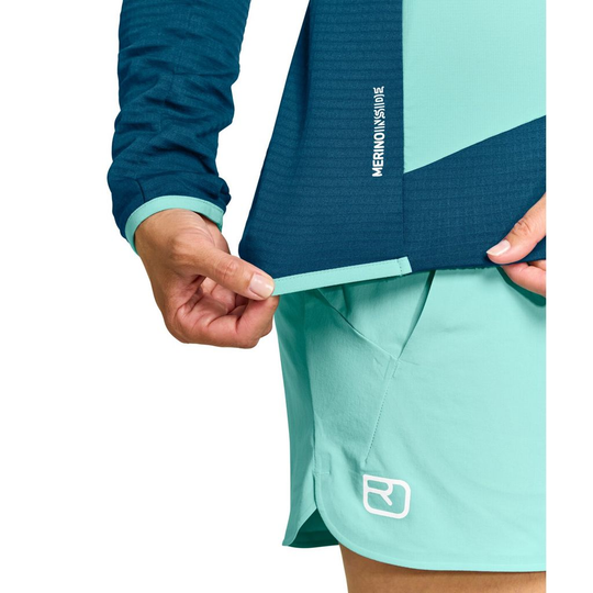 Women's Ladiz Hybrid Jacket with windproof inserts, athletic fit, featuring Merino Fleece Light Grid material, shown in use.