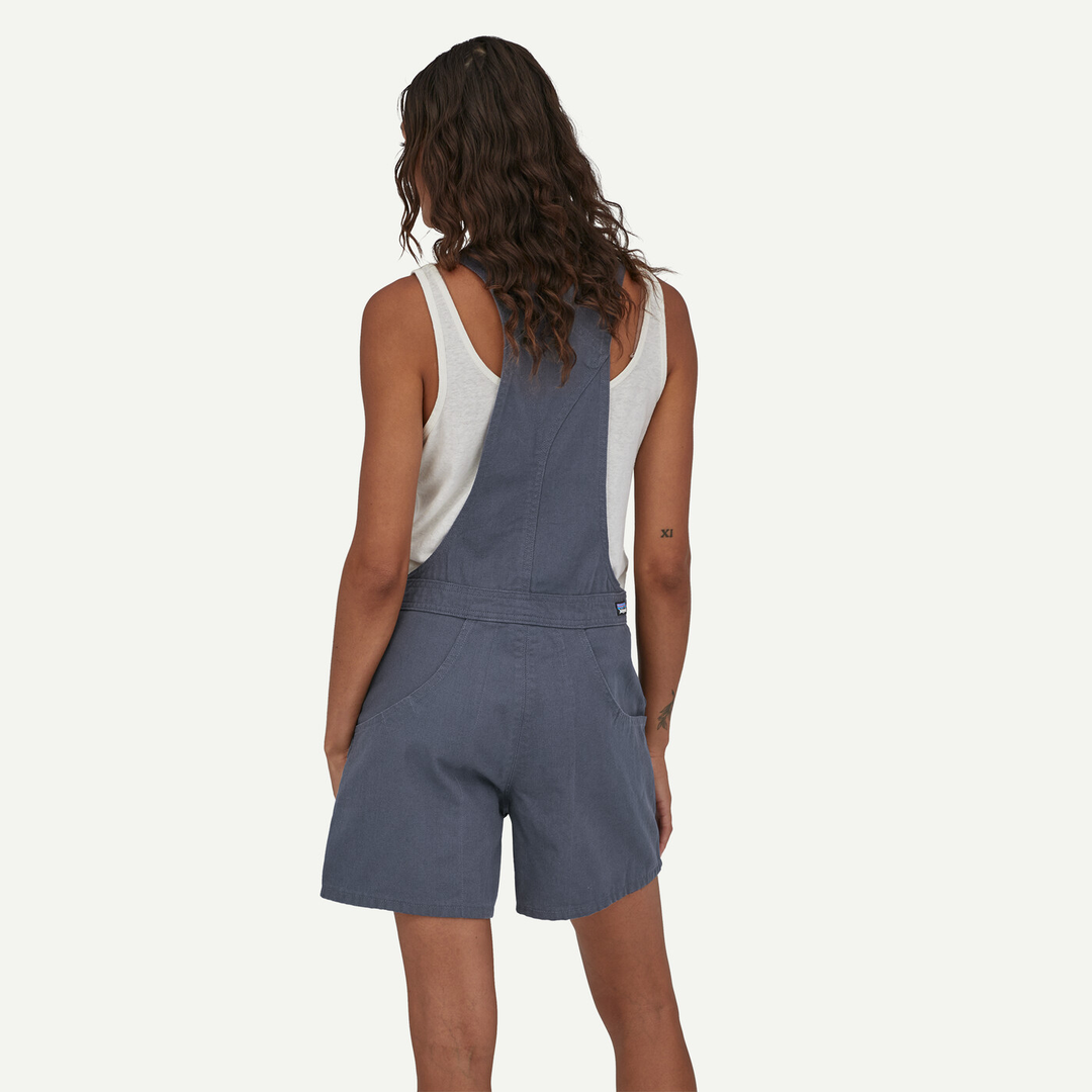Woman wearing blue W's Stand Up Overalls made of 100% organic cotton, showing adjustable straps and deep side pockets.