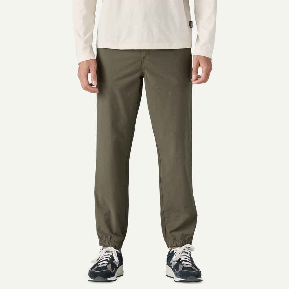 M's Nomader Joggers, comfortable and durable joggers, made from organic cotton, recycled polyester, and elastane, shown in green color, perfect for travel.