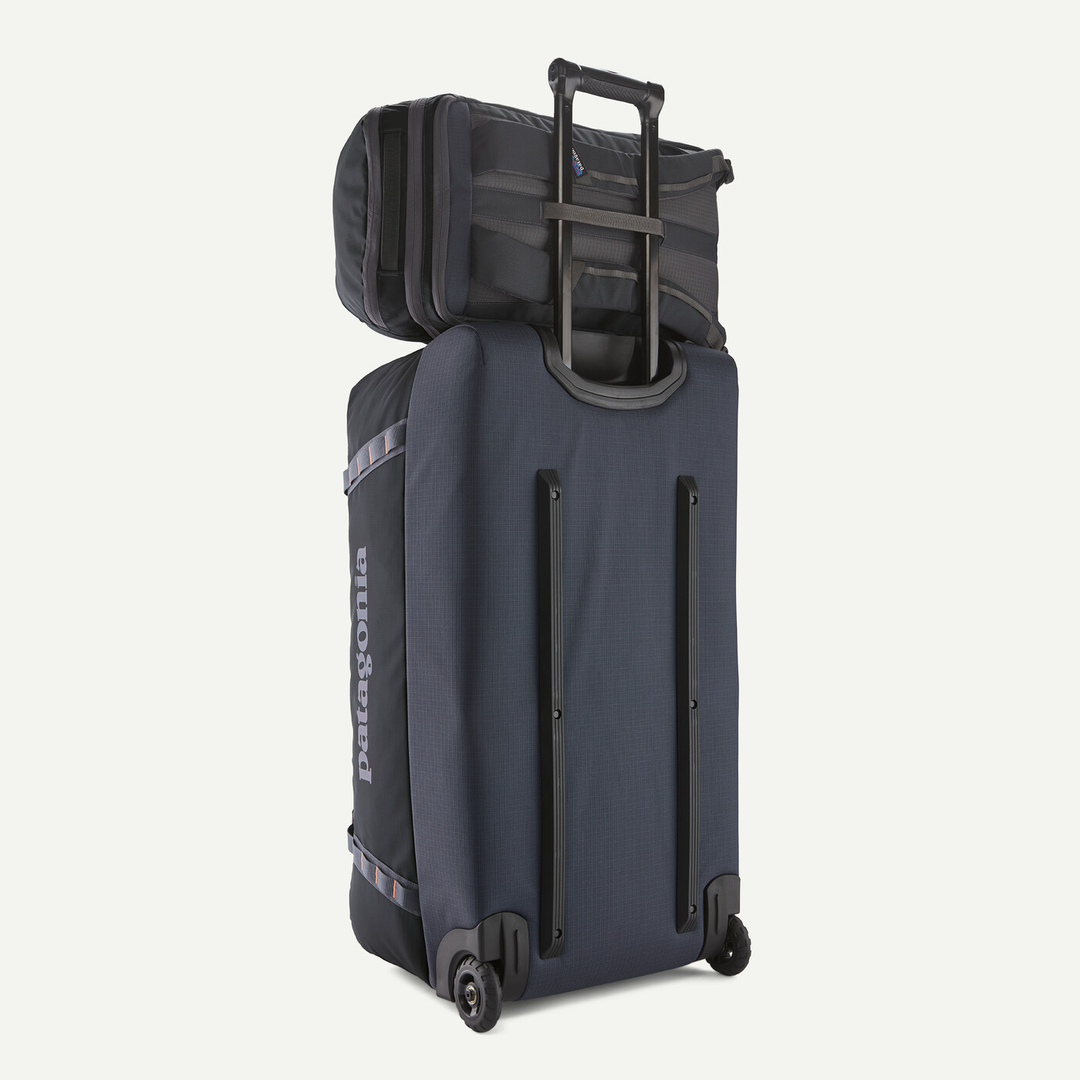 Black Hole Pack 32L attached to a trolley with telescopic handle, featuring durable recycled polyester and TPU fabric.