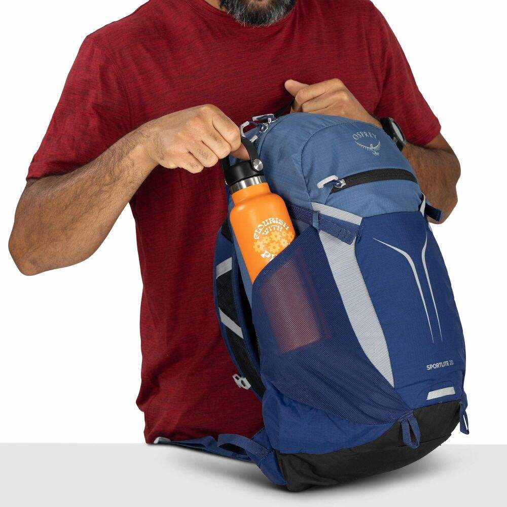 Zaino giornaliero blu e azzurro in nylon, con tasche laterali elasticizzate e borraccia arancione visibile.