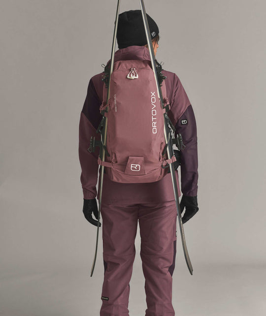 Ortovox Venet Tour 28 S Dusk Rose, indossato con sci fissati lateralmente