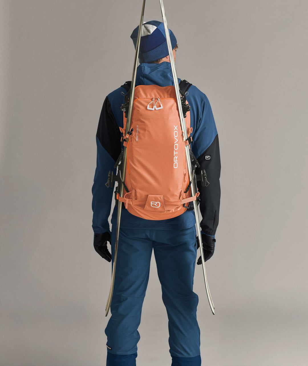 Ortovox Venet Tour 30 Faded Tangerine, indossato con sci fissati lateralmente