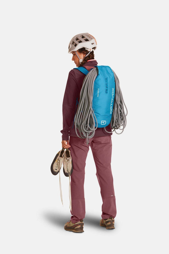 Lightweight Trad Zero 18 alpine climbing backpack, blue with rope attachment, worn by hiker.